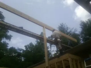 Carpenter setting a ridge beam over a new addition frame — Ice Dam Removal by Roofing Brothers in Conetoe