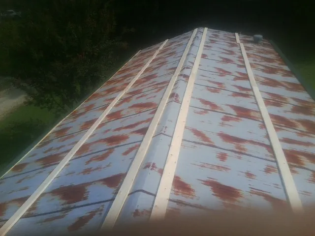 Rusted metal roof panels with new wood purlins before replacement — Storm Damage Roof Repair in Conetoe by Roofing Brothers
