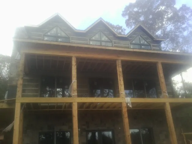 Dormers and porch framing on a large log home under construction — Roof Coating work by our crew in Conetoe