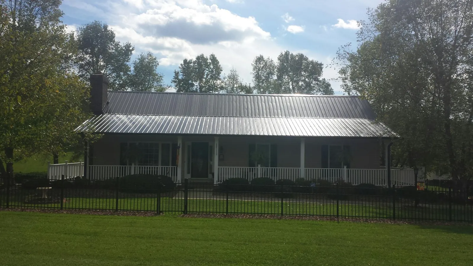 Gray metal roof on a brick ranch with a full width front porch — Gutter Guard Installation work by our crew in Conetoe