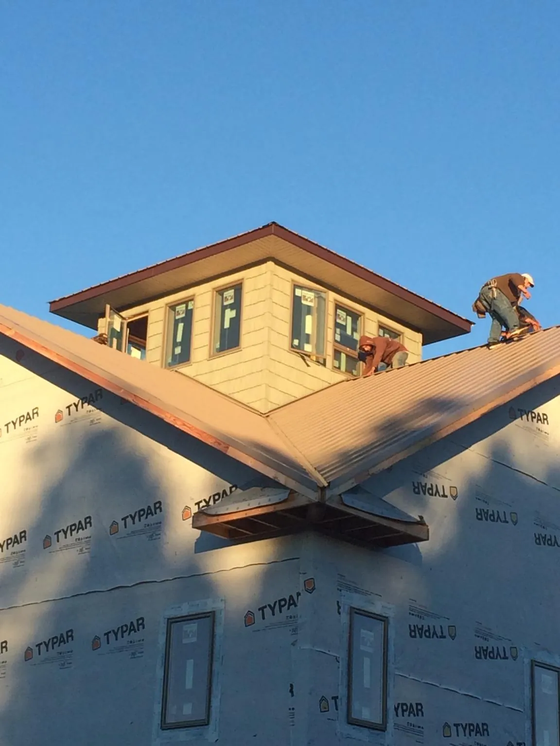Roofers working around a rooftop cupola on a new metal roof at sunset — Roof Waterproofing in Conetoe by Roofing Brothers
